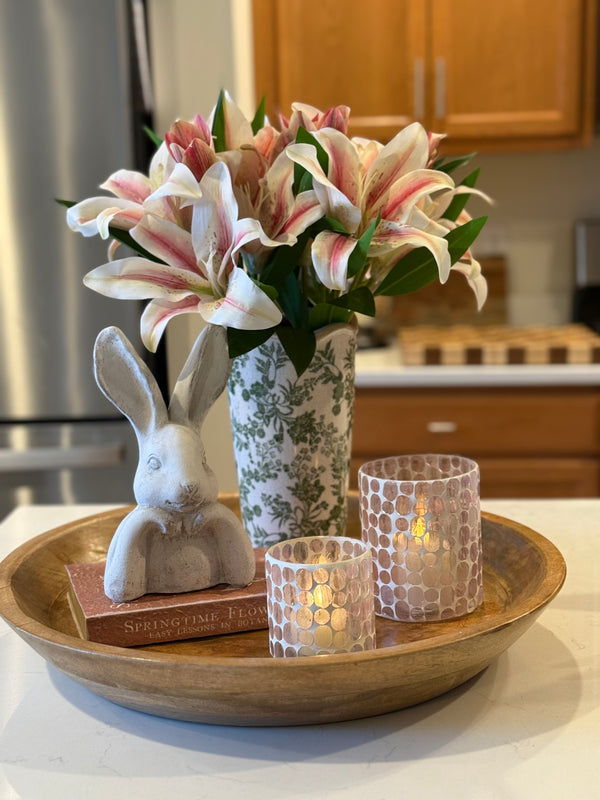 Soft pink lilies, warm candlelight, and the sweetest little bunny detail… this is how you welcome spring home 🤍Layered on a natural wood tray, this look blends texture and glow so effortlessly. The green floral vase brings a fresh garden feel, while the mosaic glass votives cast the prettiest warm shimmer once lit. And that neutral bunny? The perfect subtle touch of charm without feeling overdone.It’s simple. It’s curated. It feels lived in and loved.Style it on your kitchen island, coffee table, or entryway to create a moment that feels intentional and beautifully pulled together — without trying too hard. 🌸✨
